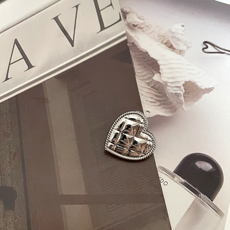 Botón corazón metálico plata brillante con borde trenzado oscuro y relieve facetado