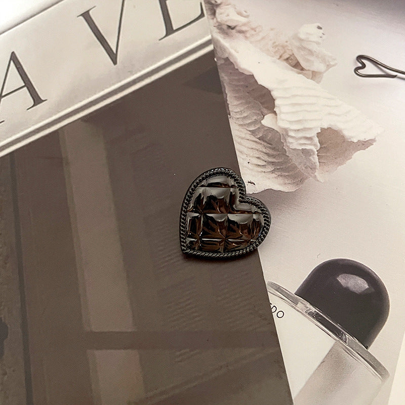 Botón corazón metálico negro (gun black), borde trenzado, relieve geométrico brillante