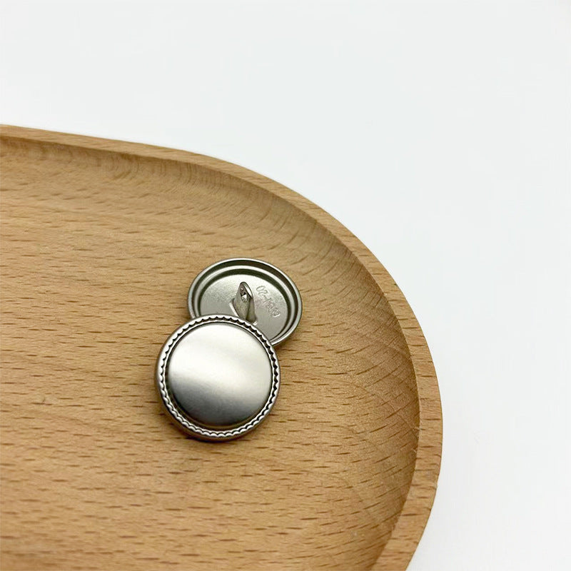 Matte silver round metal shank button with serrated edge, showing back view