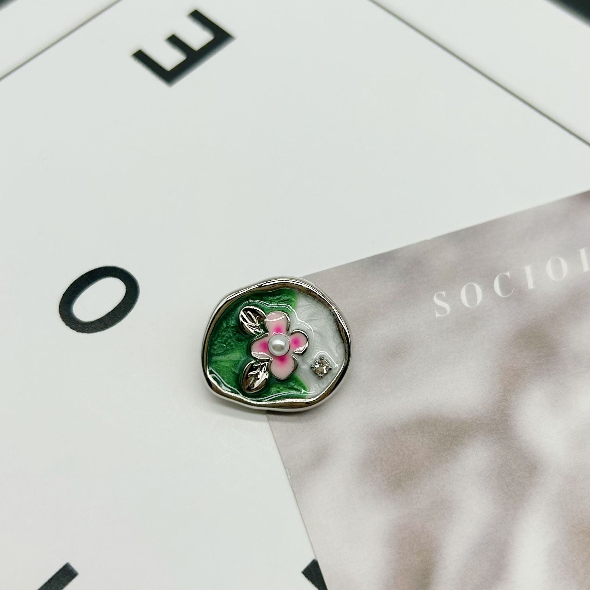 Silver oval flower button with green leaf enamel, pink petals and pearl center
