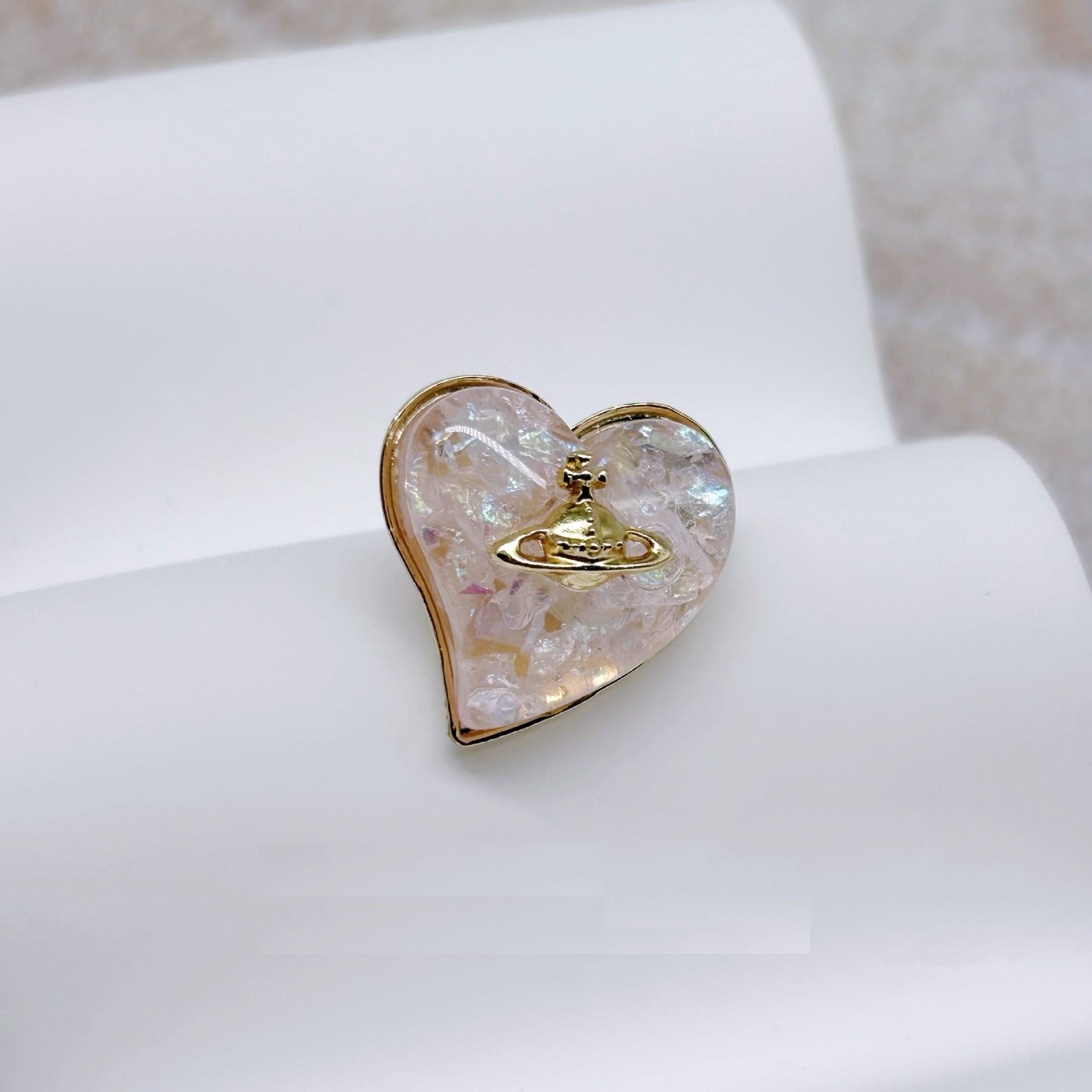 Single heart-shaped metal and resin button, iridescent front with gold-tone emblem