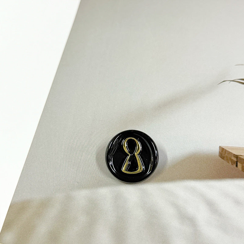 23mm round button, black with golden-lined miniature figure icon on the face