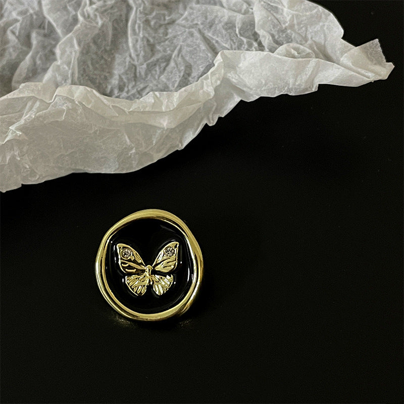 Gold-edged round button with diamond butterfly detail on black enamel-style center