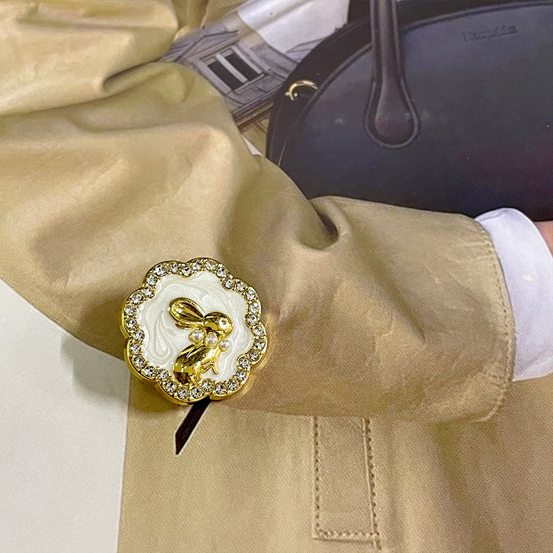Gold bunny suit button with white swirl pearl inlay and rhinestone border