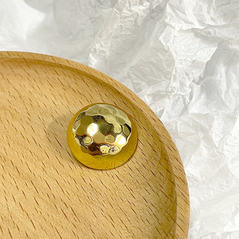 Gold mushroom-shaped shiny button, reflective metallic face with raised texture