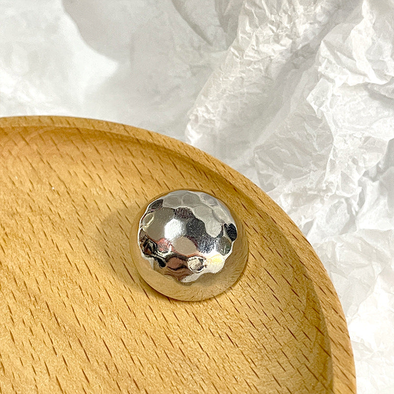 Silver mushroom-shaped shiny metal button with shank, reflective textured front