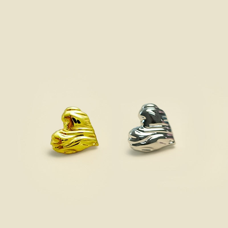 Small heart-shaped metal buttons in gold and silver, reflective finish