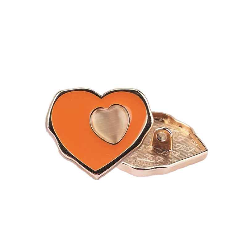 Orange heart sewing button with gold-tone back and raised heart center