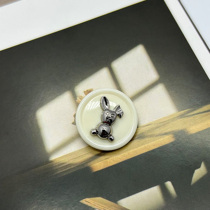 Cream resin rabbit round button with silver-tone metal rabbit details, dual-tone design.