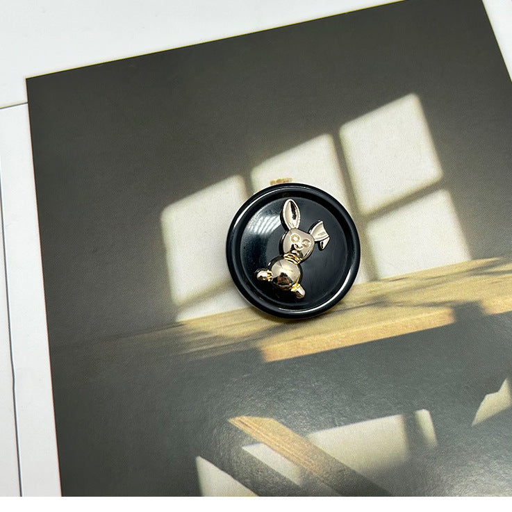 Black resin rabbit round button with gold-tone metal rabbit details, dual-tone design.