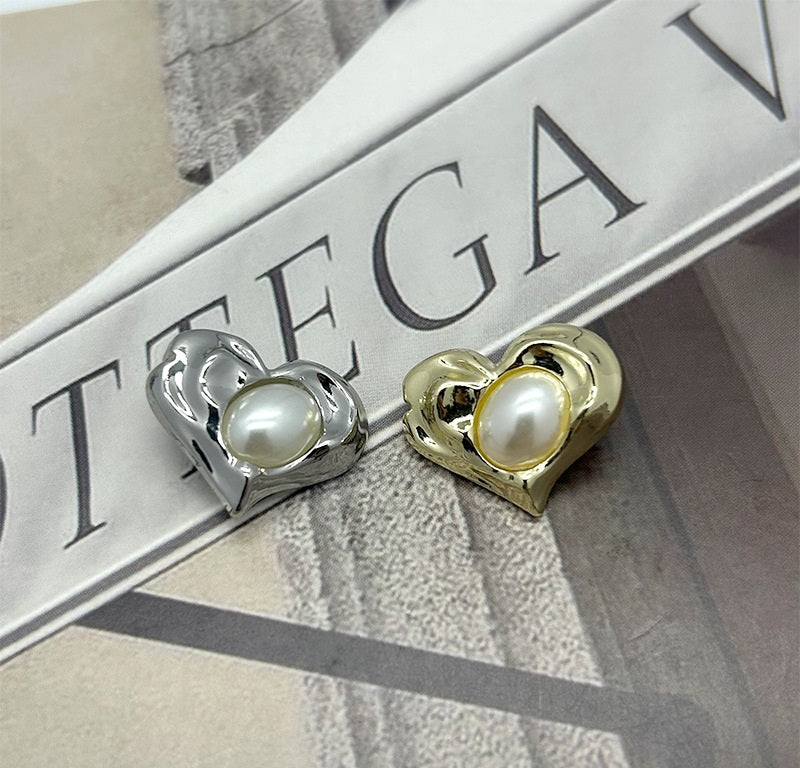 Two heart-shaped pearl buttons: silver and gold metal with white pearl centers