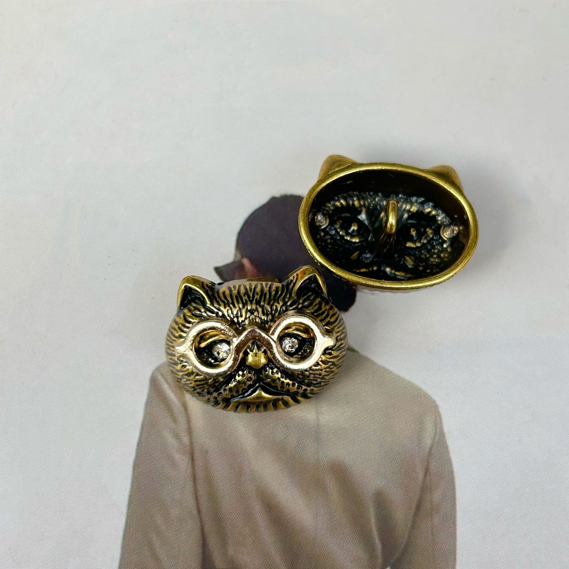 Antique gold cat-head sewing button with dark inlay, raised eyes, whisker texture