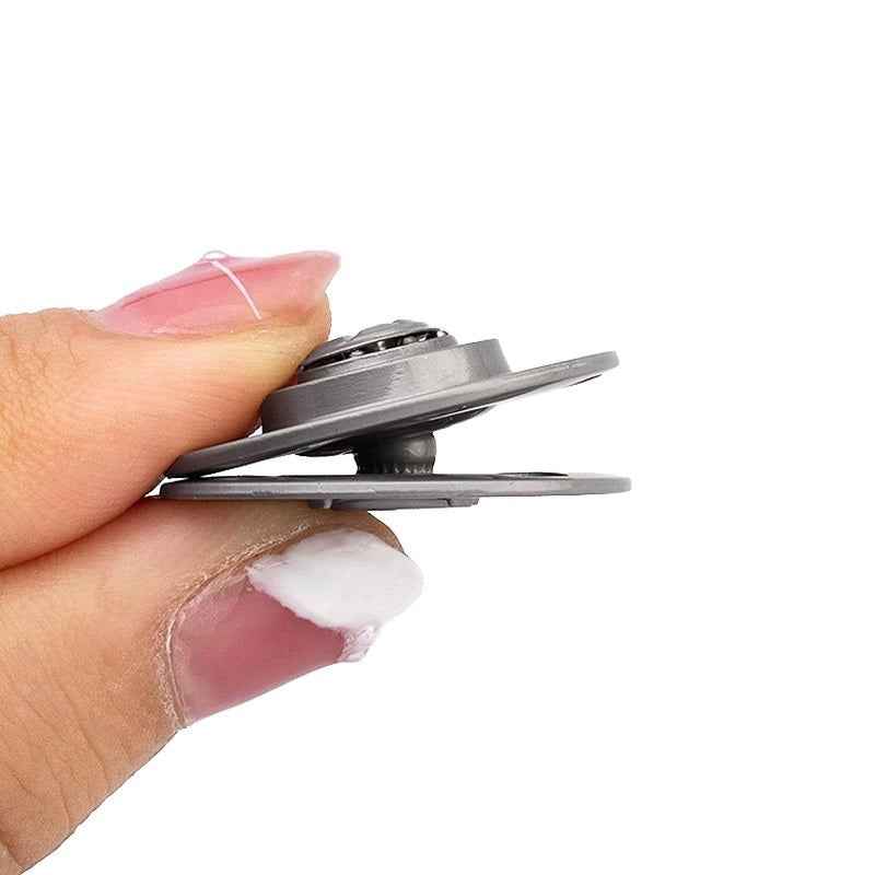 Hand holding dark metal hidden snap buttons; round discs with 4 mounting notches