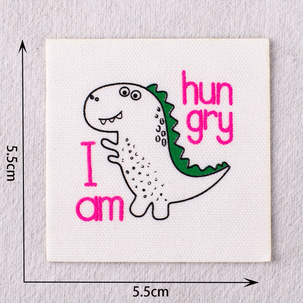 Pink-and-green dinosaur patch with text “hun gry” and “I am” letters