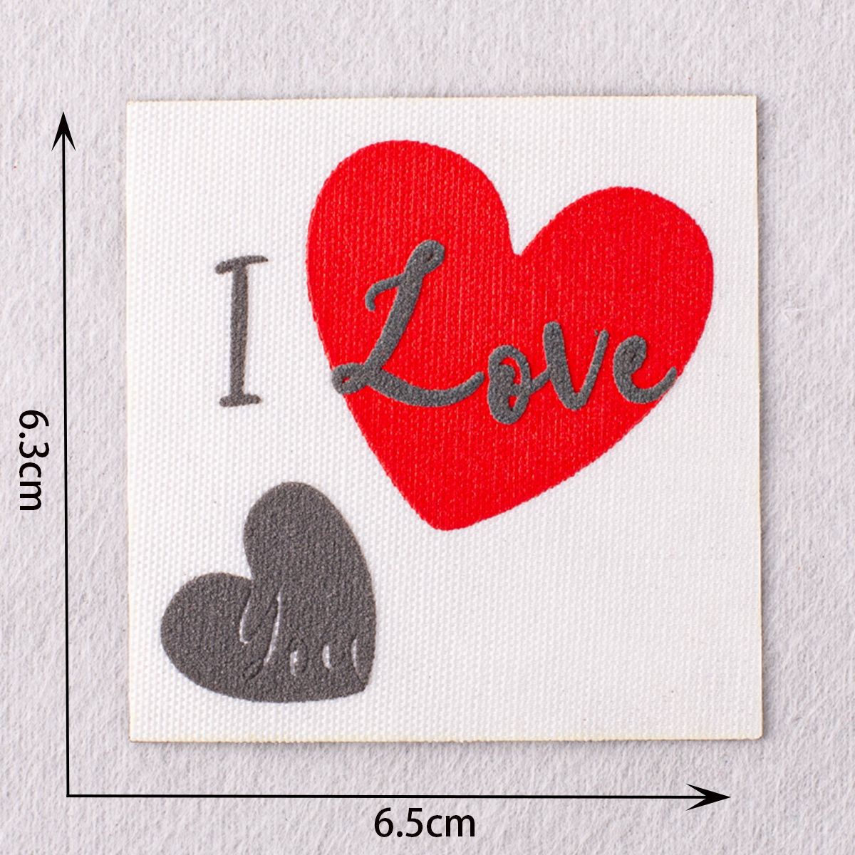 Red heart “Love” patch with grey heart at bottom and small cross text