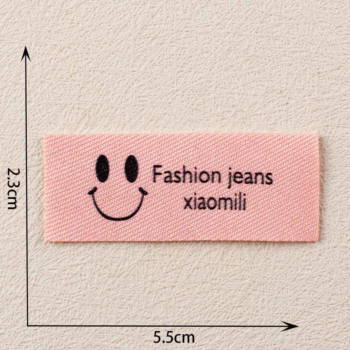 Pink fabric label with smiley, Fashion jeans xiaomili, ~5.5×2.3 cm