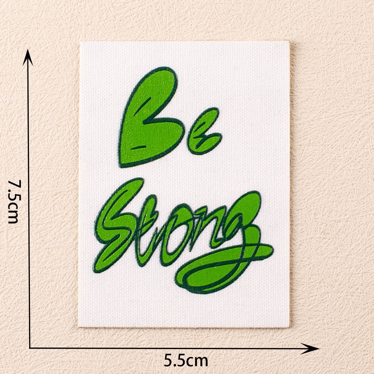 White fabric patch with green heart and 'Be Strong' script, self-adhesive