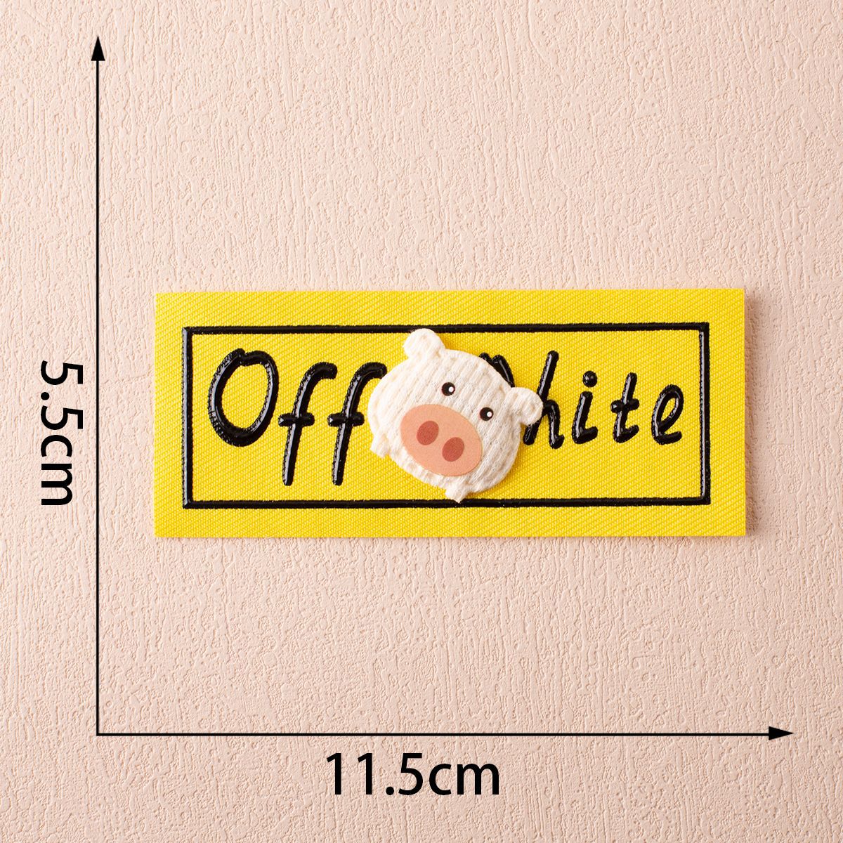 Off-White fabric label on yellow with pig-face appliqué and stitched lettering