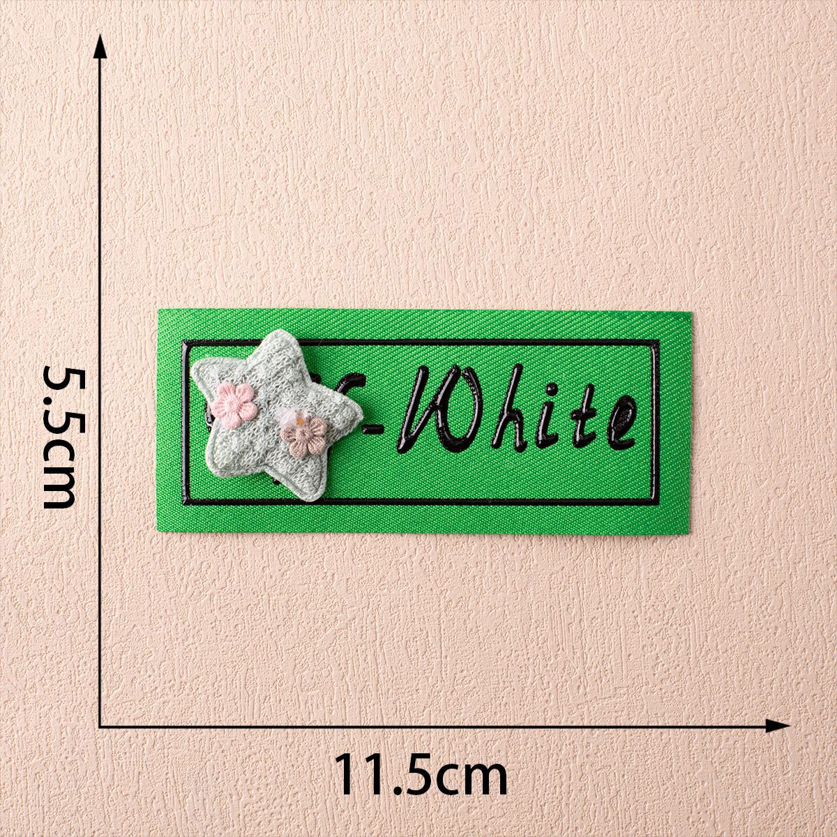 Off-White fabric label on green with star appliqué and pink flower detail