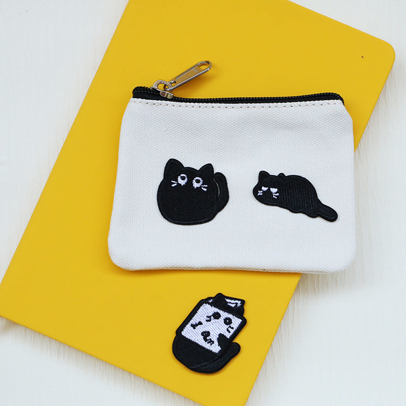 Zipper pouch with two stitched black cat patches and one smaller patch below