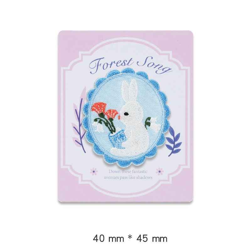 Forest Song embroidered adhesive patch: blue scalloped circle with white rabbit and red flower