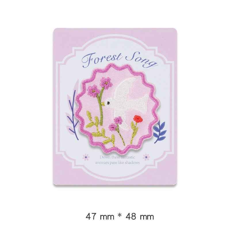 Forest Song embroidered adhesive patch: pink scalloped circle with flowers and white animal