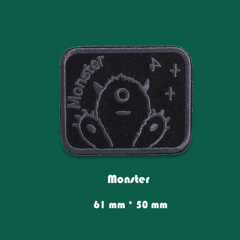 Black embroidered badge patch with monster character faces and symbols, 61mm x 50mm