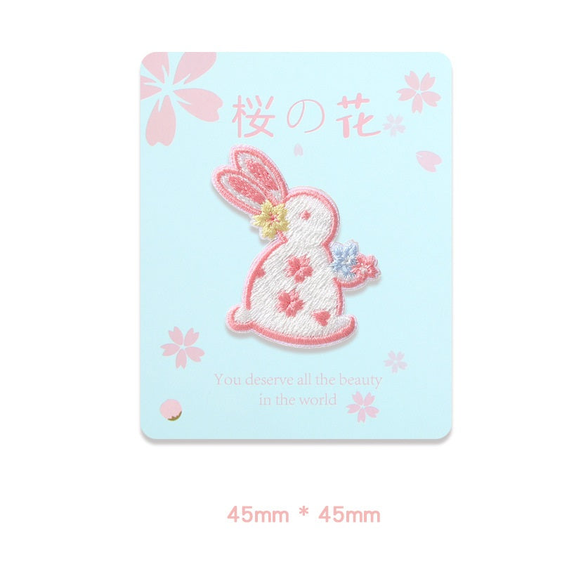 Self-adhesive embroidered rabbit patch holding flowers, 45x45mm