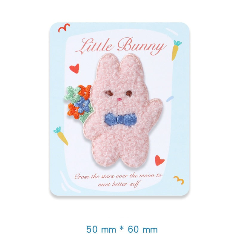 Pink plush bunny embroidered adhesive patch, holding a small multicolor flower
