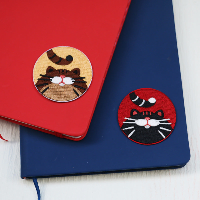 Round embroidered kitten patches on fabric: tan cat face and dark red cat face