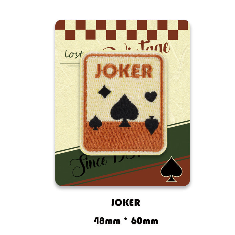 Joker card embroidered patch, tan border with black spade symbols.