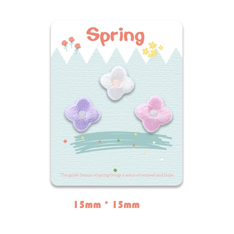 Self-adhesive embroidered flower trio: white, lavender, and pink petals, satin stitch
