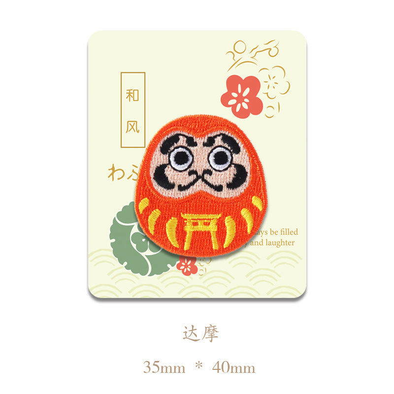 Orange daruma-style face embroidered patch with big eyes; 35mm x 40mm