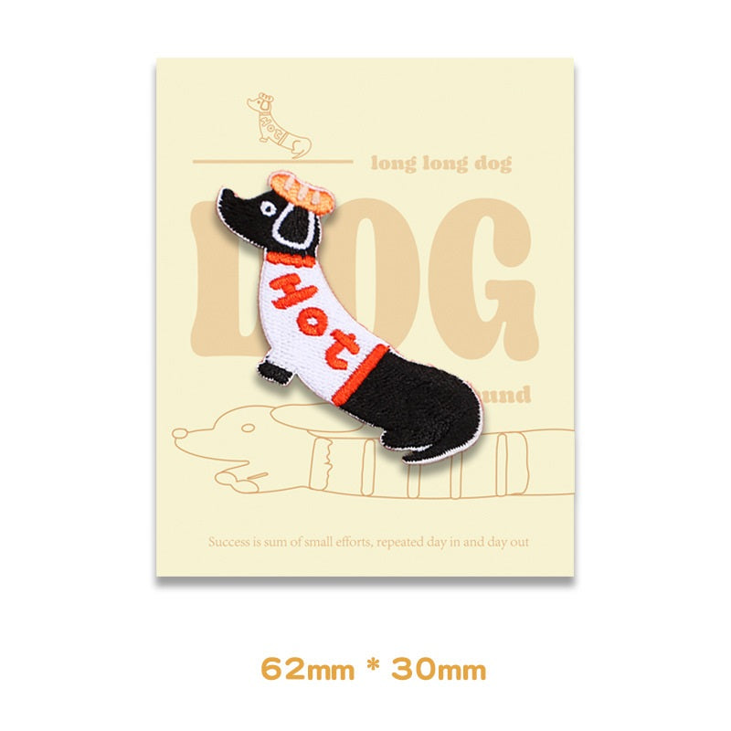 Embroidered dachshund patch in white/black with orange text, 62 x 30 mm