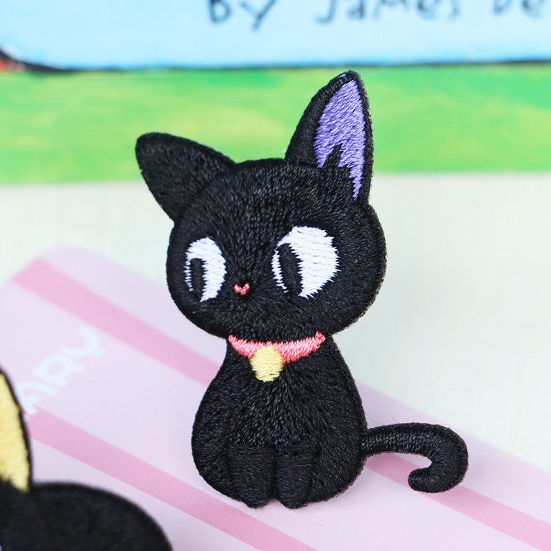 Schwarzes Katzen-Patch im Close-up, besticktes Gesicht mit gelbem Halsband und Pfötchen