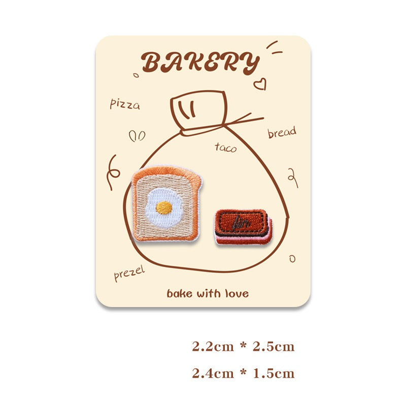 Card with two mini embroidered baking patches: pretzel and dark biscuit bar.