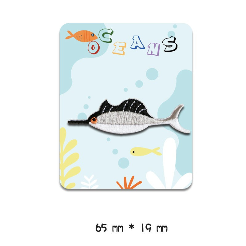 Gray-and-black striped fish embroidered patch with orange eye, 65 mm x 19 mm, self-adhesive