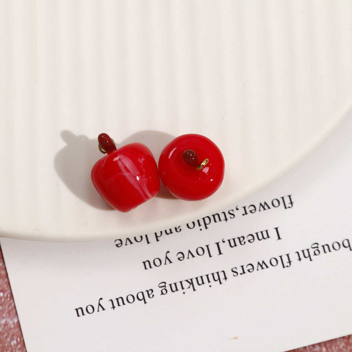 Red cut-half apple resin pendants, two glossy halves with metal loops