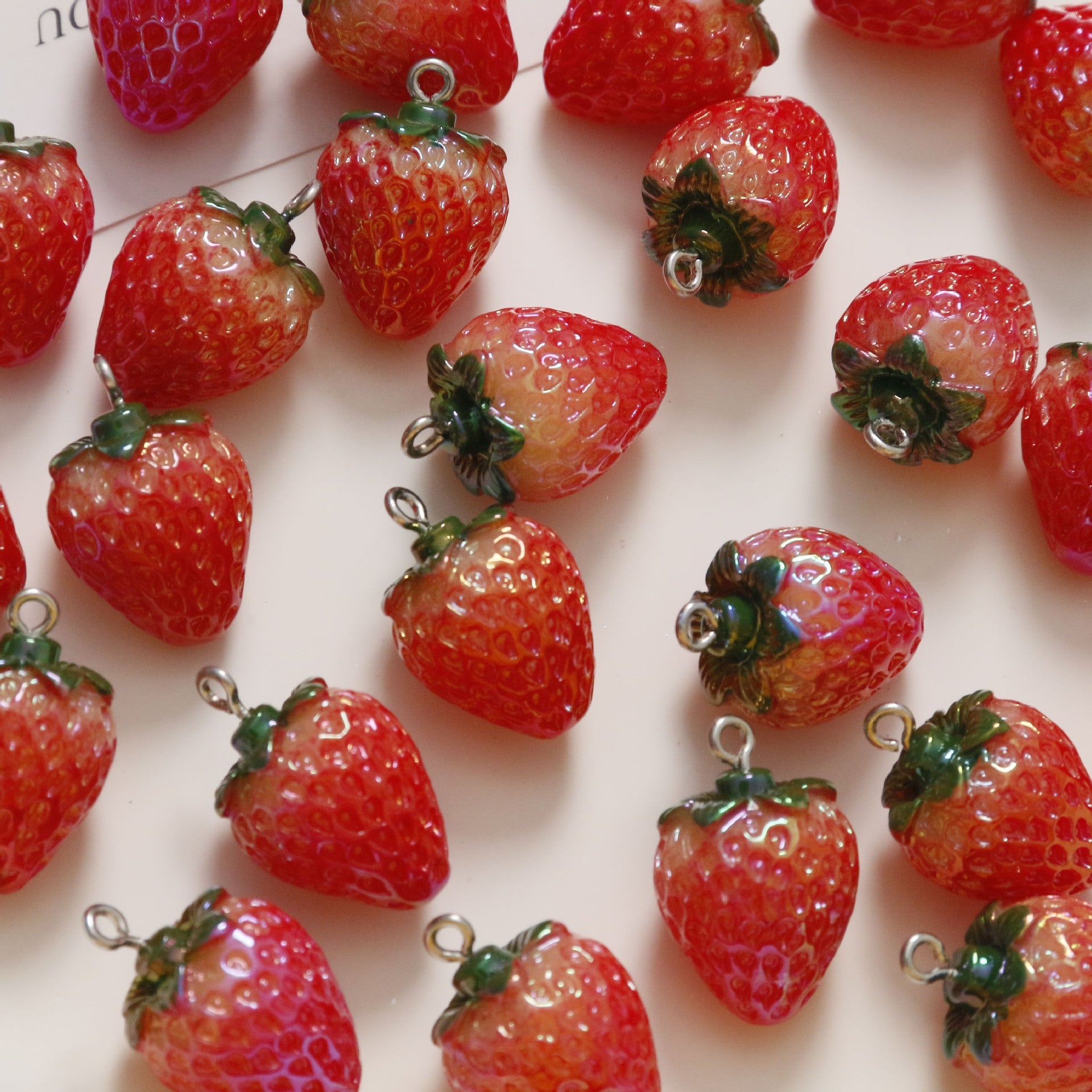 Close-up of red resin strawberry pendants with green leaves and silver loops