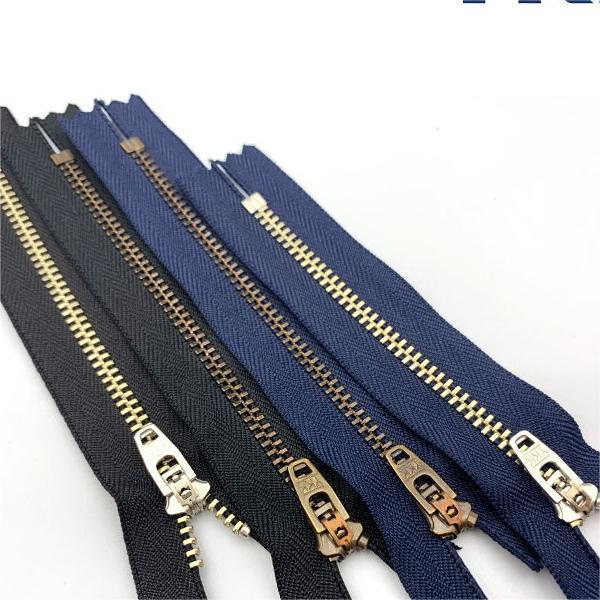 Metal closed-end zippers set with black and navy tapes, brass teeth and sliders